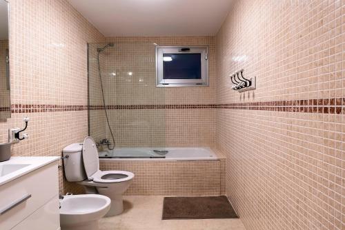 ein Bad mit einem WC und einer Badewanne sowie einen TV in der Unterkunft Villa La Perla - Cliffside Retreat in Antigua