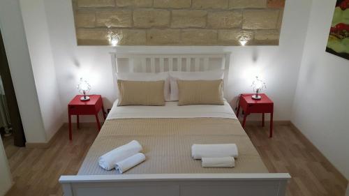 a bedroom with a large bed with two red tables at NoMapartments Il Cortile Romey in Trapani
