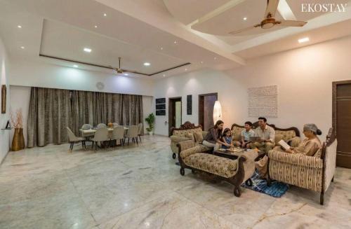 eine Gruppe von Menschen sitzt in einem Wohnzimmer in der Unterkunft EKO STAY Gold- CHESTNUT VILLA in Karjat