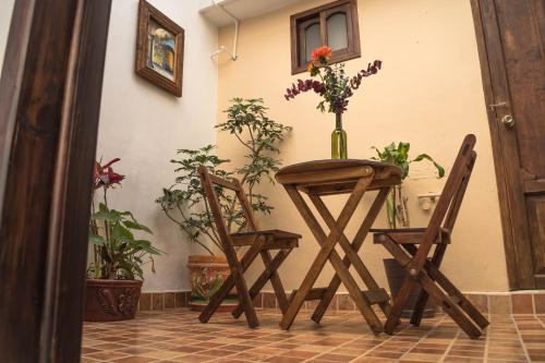 una mesa con dos sillas y un jarrón con flores. en Hotel Posada Dominnycos en San Cristóbal de Las Casas
