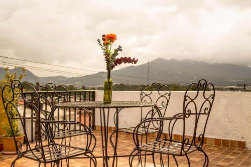 una mesa y sillas con un jarrón con flores en Hotel Posada Dominnycos en San Cristóbal de Las Casas