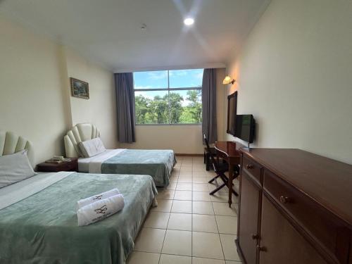 a hotel room with two beds and a television at Golden Village Hotel 