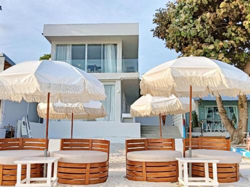 deux parasols, tables et chaises devant un bâtiment dans l'établissement Sawasdee Coco Resort, à Ko Samet