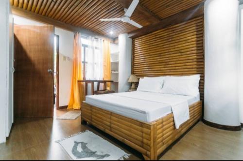 een slaapkamer met een groot bed met een houten wand bij Paras Inn Boracay in Boracay