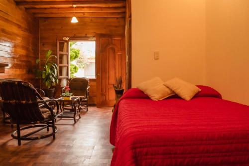 1 dormitorio con cama roja, mesa y sillas en Chalet Dominnycos, en San Cristóbal de Las Casas