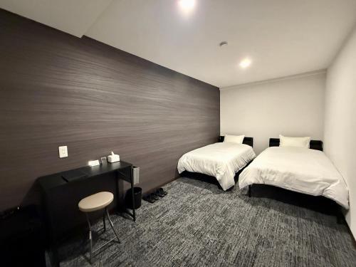 ein Hotelzimmer mit zwei Betten und einem Schreibtisch in der Unterkunft HOTEL STAY Plus in Imabari