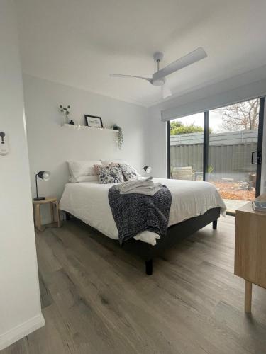 a white bedroom with a bed and a large window at WARM Sunlit Sustainable north facing Studio in Hawker
