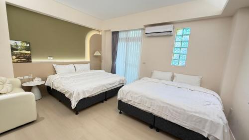 een slaapkamer met twee bedden en een bank en een raam bij 山邸民宿 in Taitung
