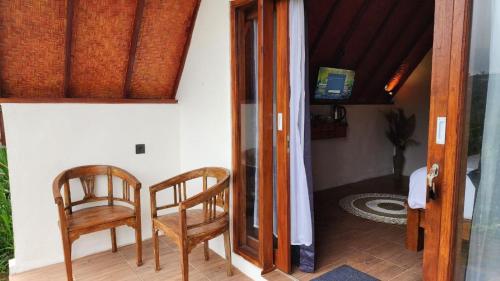 une porte ouverte menant à une chambre avec deux chaises dans l'établissement Pondok Kanginan, à Plaga
