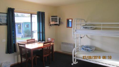 a room with a desk and bunk beds and a table at Catlins Newhaven Holiday Park in Owaka