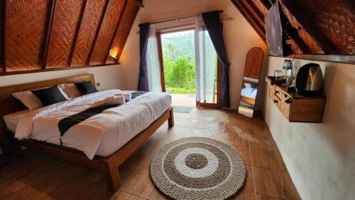une chambre avec un grand lit et une grande fenêtre dans l'établissement Pondok Kanginan, à Plaga