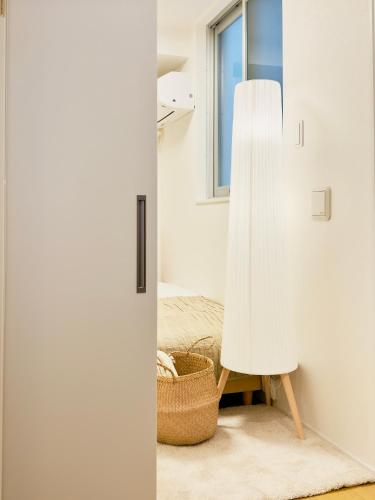 a white room with a white lamp and a basket at Kyo-wa Hotel Kinshicho in Tokyo
