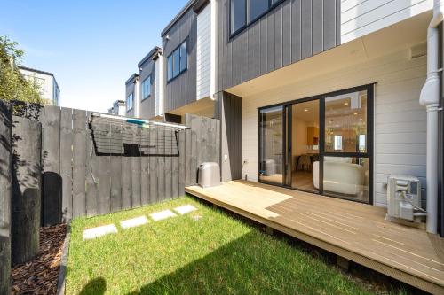 einen Hinterhof mit einer Holzterrasse neben einem Haus in der Unterkunft Glen Eden Haven in Auckland
