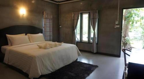 een slaapkamer met een groot wit bed met een raam bij V Valley Resort in Satun