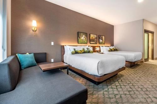 a hotel room with two beds and a couch at Cambria Hotel Louisville Downtown-Whiskey Row in Louisville