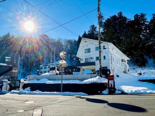 a snowcovered street with a building and the sun at Yuzawa house2 in Yuzawa