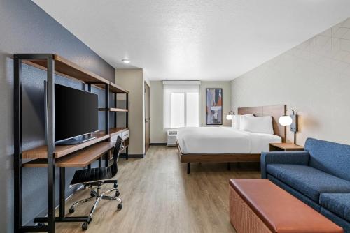 een hotelkamer met een bed en een bureau met een televisie bij Everhome Suites Rochester Greece in Rochester