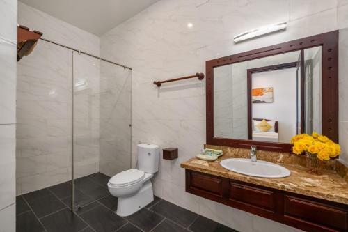een badkamer met een toilet, een wastafel en een spiegel bij Paradise Boutique Hoi An in Hội An