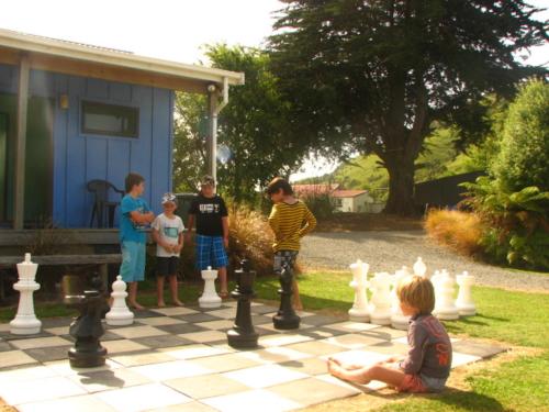 a group of children playing chess on a chessboard at Catlins Newhaven Holiday Park in Owaka
