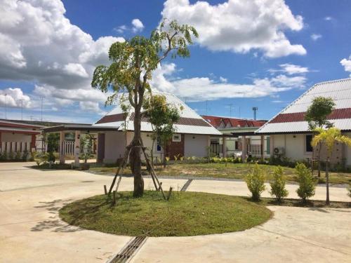 een boom in een cirkel voor een gebouw bij Suanrak Resort in Suphan Buri