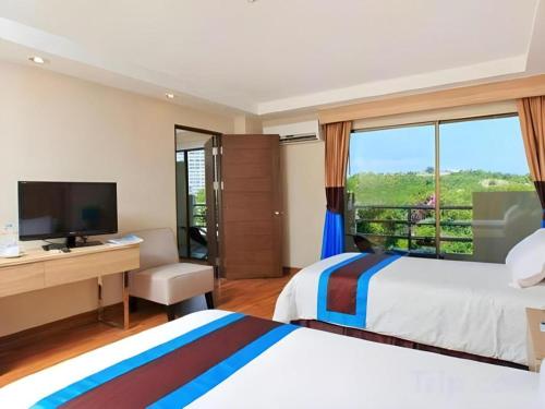 ein Hotelzimmer mit einem Bett, einem Schreibtisch und einem Fenster in der Unterkunft Blue Wave Hotel Hua Hin in Hua Hin