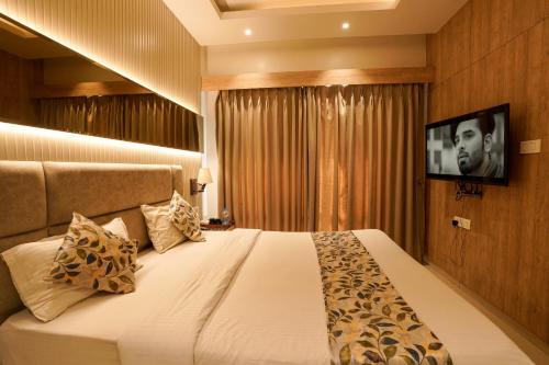 Schlafzimmer mit einem Bett und einem TV an der Wand in der Unterkunft The Food Villa in Mumbai