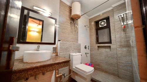 a bathroom with a sink and a toilet and a mirror at Hotel Rustam Residency sec-39 in Gurgaon