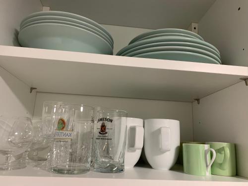 ein Küchenregal mit Tassen und Tellern darauf in der Unterkunft Cosy New Studio 2 min RER B in Aulnay-sous-Bois