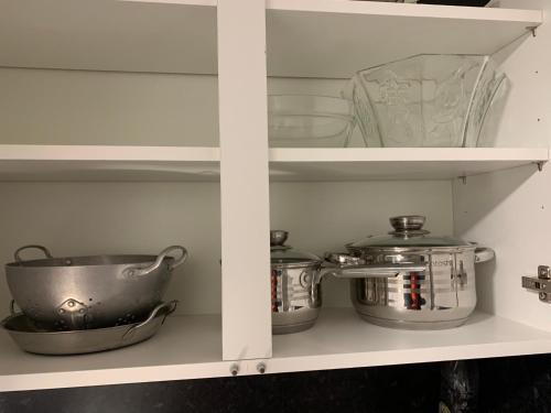 ein Regal mit Töpfen und Pfannen und einer Teekanne in der Unterkunft Cosy New Studio 2 min RER B in Aulnay-sous-Bois