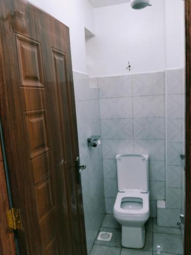 a bathroom with a white toilet and a door at Kinara suites in Kiambu