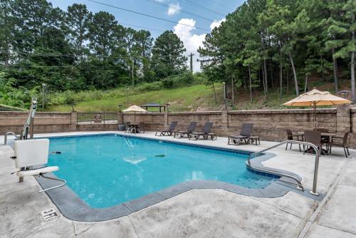 a swimming pool with chairs and an umbrella at Comfort Inn Birmingham Homewood in Birmingham