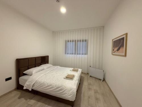 a bedroom with a bed with white sheets and a window at Milmari kop in Raška