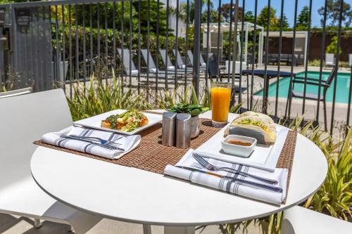 a white table with food and drinks on it next to a pool at Cambria Hotel LAX in El Segundo