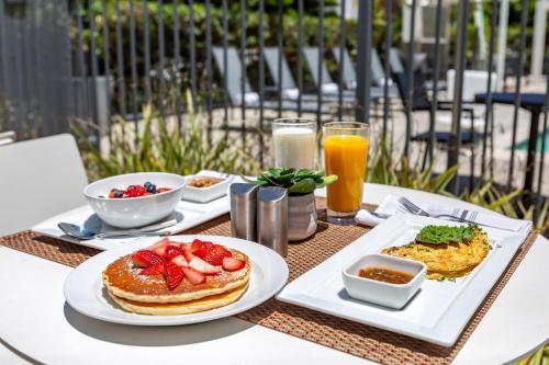 a table topped with plates of breakfast food and orange juice at Cambria Hotel LAX in El Segundo