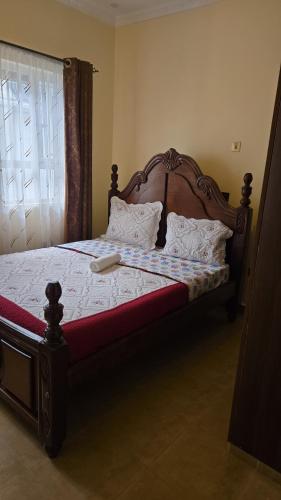 a bedroom with a large bed with a wooden headboard at Luxury Villas in Gakuo
