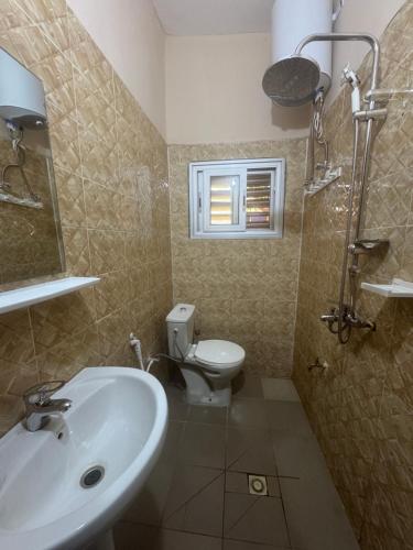 een badkamer met een wastafel en een toilet en een raam bij La maison de Kalabancoura in Bamako