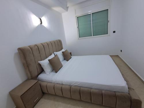 een bed in een kamer met een bank en een raam bij Baya Residentie in Temara