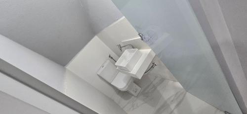 a white bathroom with a toilet and a sink at Casa Temporada Conchinha do Mar in São Mateus