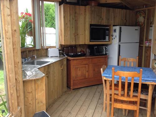 a kitchen with a table and a white refrigerator at Domaine sur une plage in Saint-Félicien