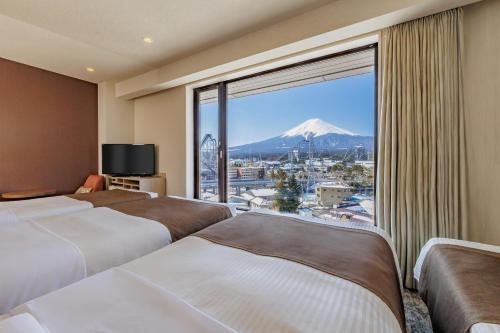 a hotel room with three beds and a view of a mountain at HOTEL MYSTAYS Fuji Onsen Resort in Fujiyoshida