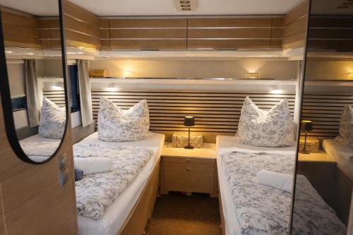 two beds in a small room with a desk at Weberhof-Münster Glamping in Münster