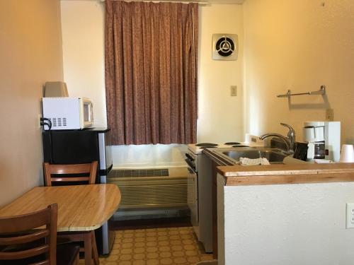 a kitchen with a sink and a table in a room at Umatilla Inn & Suites in Umatilla