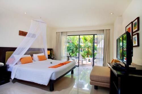 a bedroom with a large white bed and a television at Woraburi Phuket Resort & Spa - SHA Plus in Karon Beach