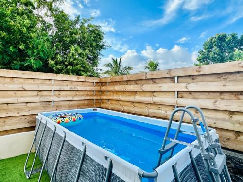 a backyard swimming pool with a wooden privacy fence at La Kaz Eden * * * * in Les Cocos