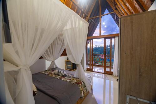 a bedroom with a bed with curtains and a window at The Pyramid Ubud River Villas in Gianyar