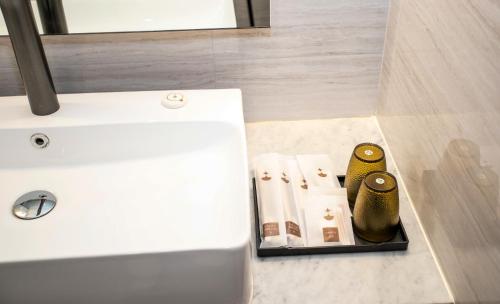 een badkamer met een wastafel en een aanrecht met enkele spullen bij Enrich Grand Hotel in Bangkok