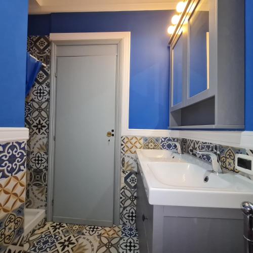 a bathroom with a white sink and a blue wall at Ocean View House in Nettuno