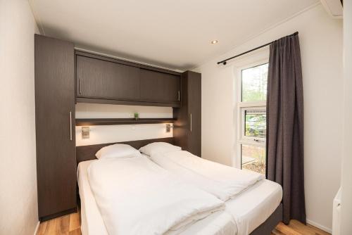 een slaapkamer met een groot wit bed met een raam bij Veluwepark de Bosgraaf in Apeldoorn