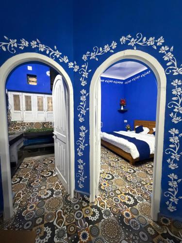a bedroom with a blue wall with a bed and an open door at Brij niwas in Udaipur