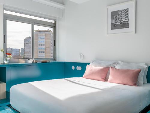 a bedroom with a blue and white bed with pink pillows at LSA Alvalade by Numa in Lisbon